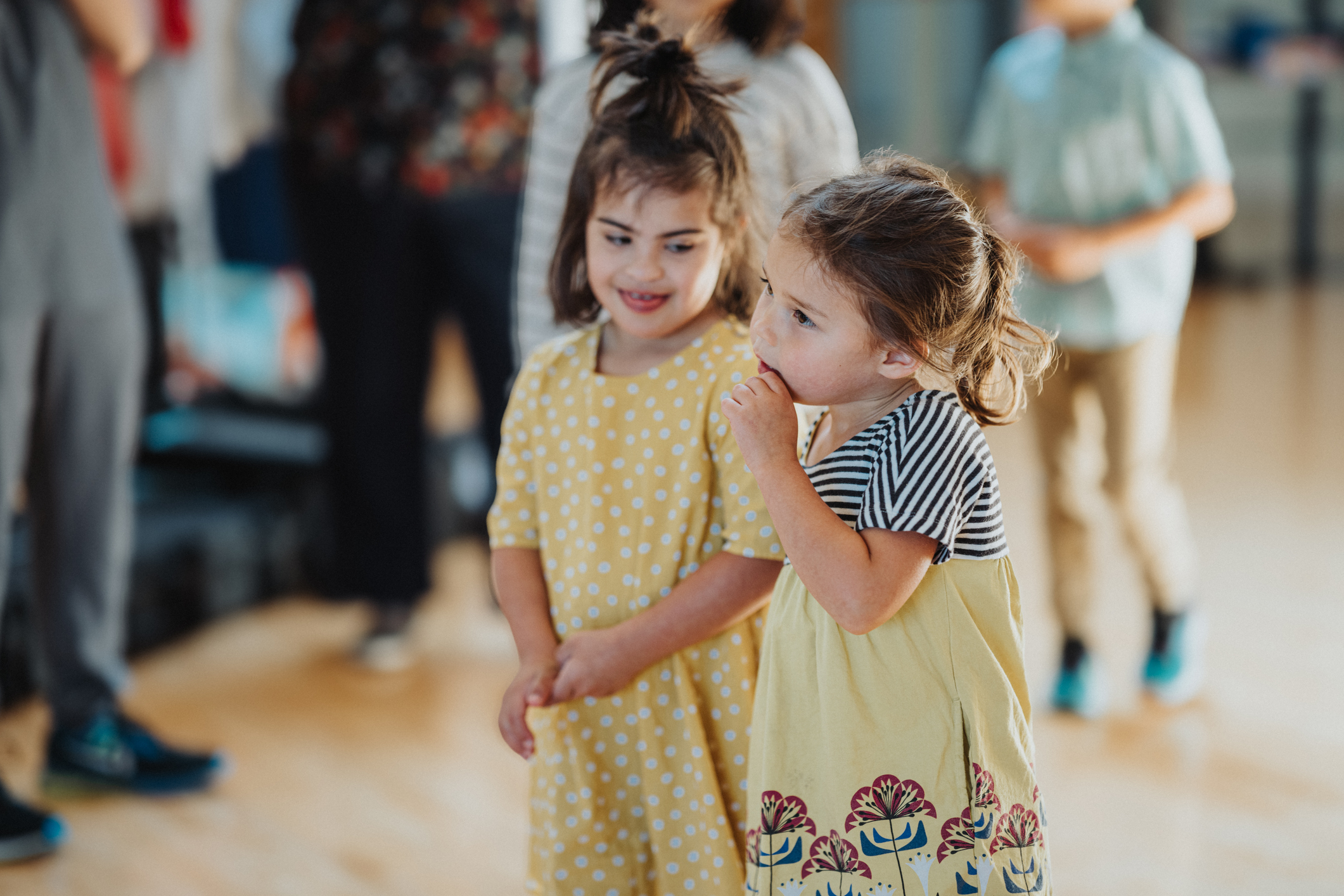 Two adorable girls of biracial ethnicities play with each other while standing in the waiting room of a doctor's office.